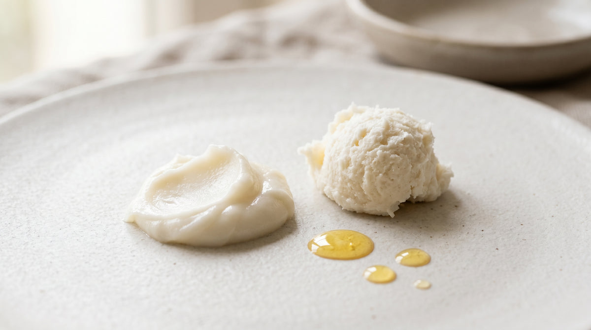 Whipped tallow-style cream and balm swatch with oil droplets on a pale surface