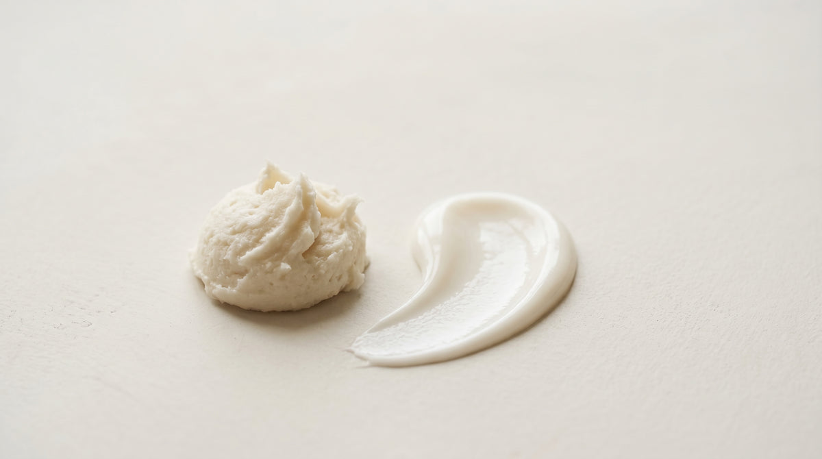 Whipped tallow balm and creamy body lotion swatches on a pale surface