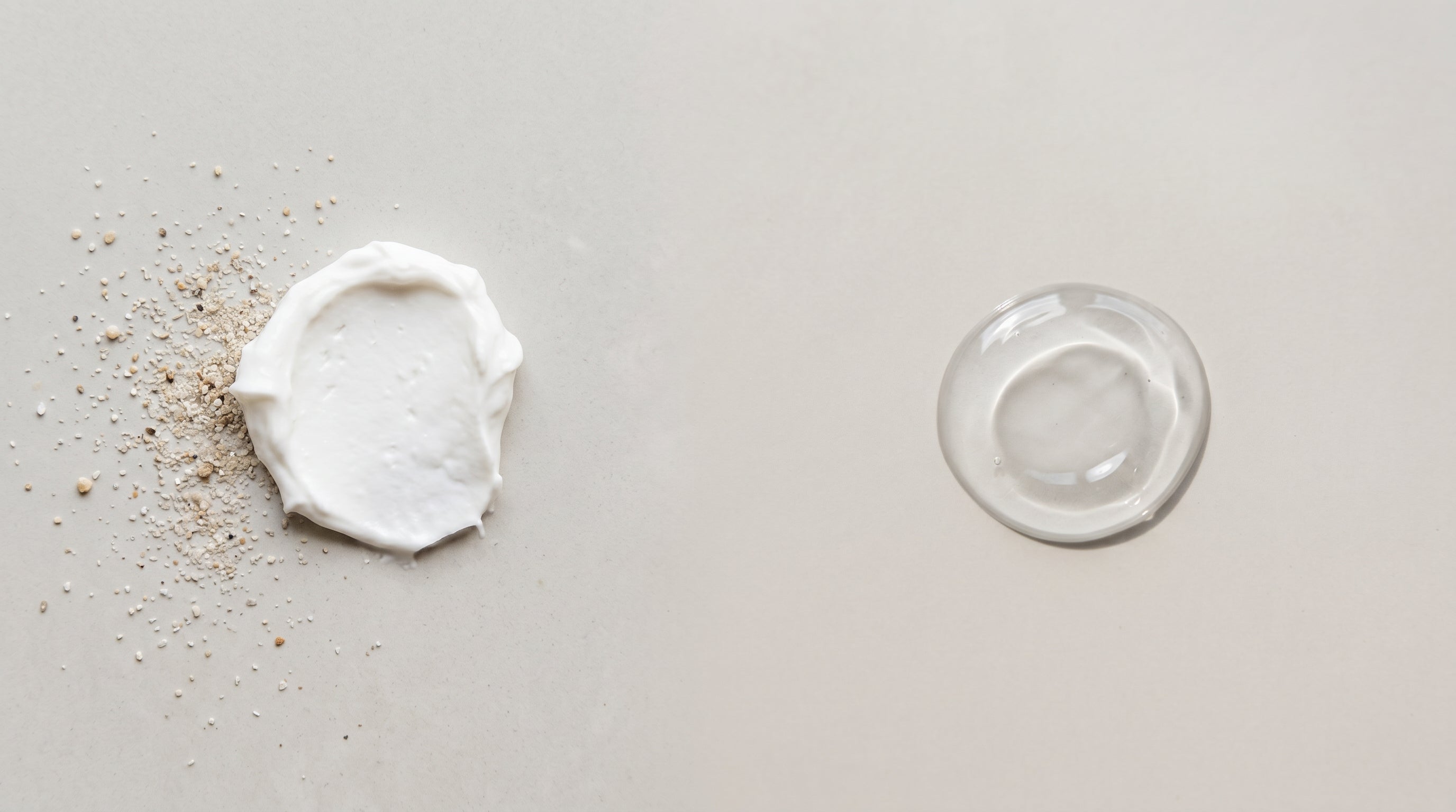 Opaque white mineral sunscreen cream beside a clear chemical sunscreen gel on a neutral surface