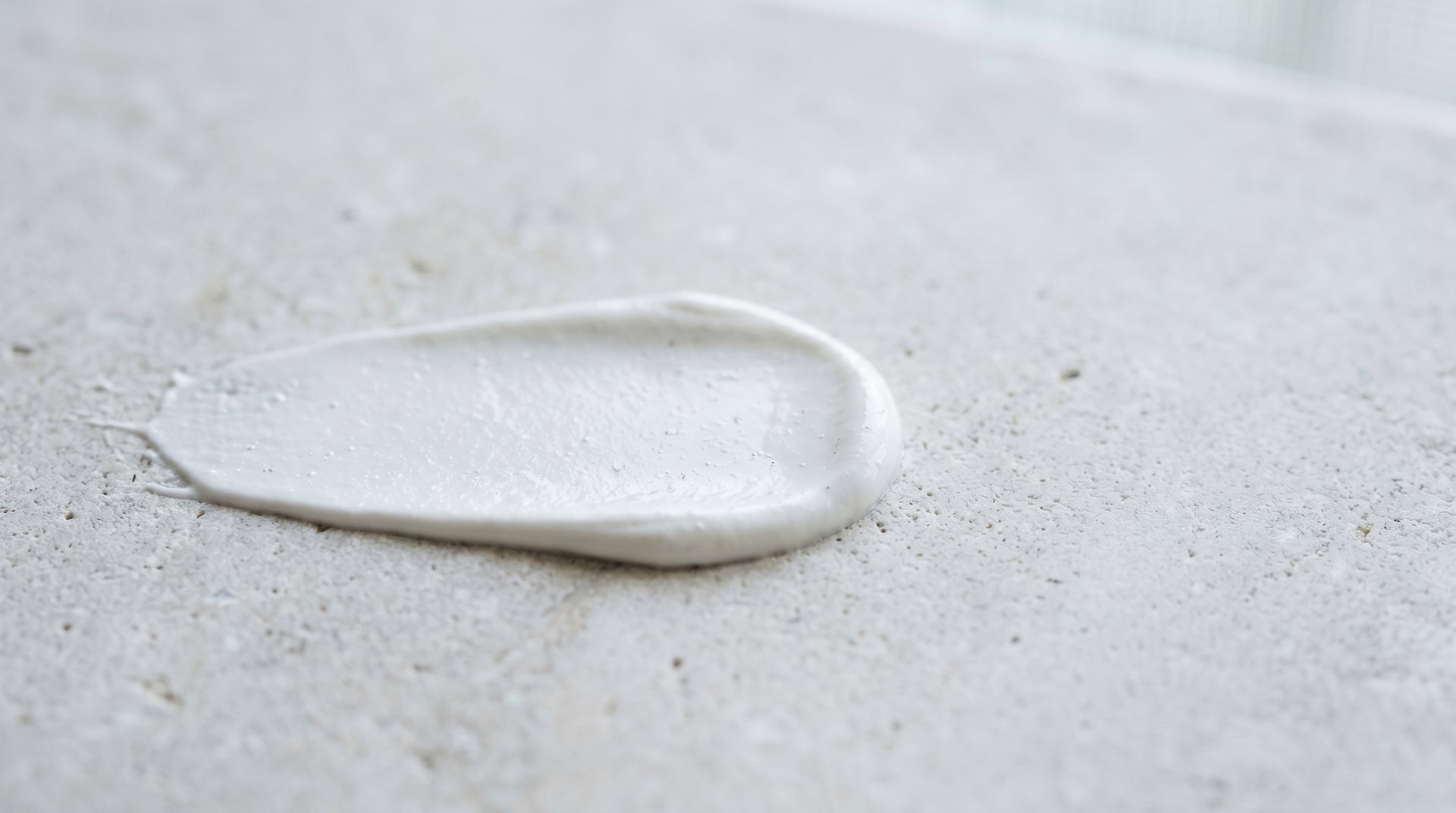 Swatch of white non-nano zinc oxide mineral sunscreen cream on a pale surface