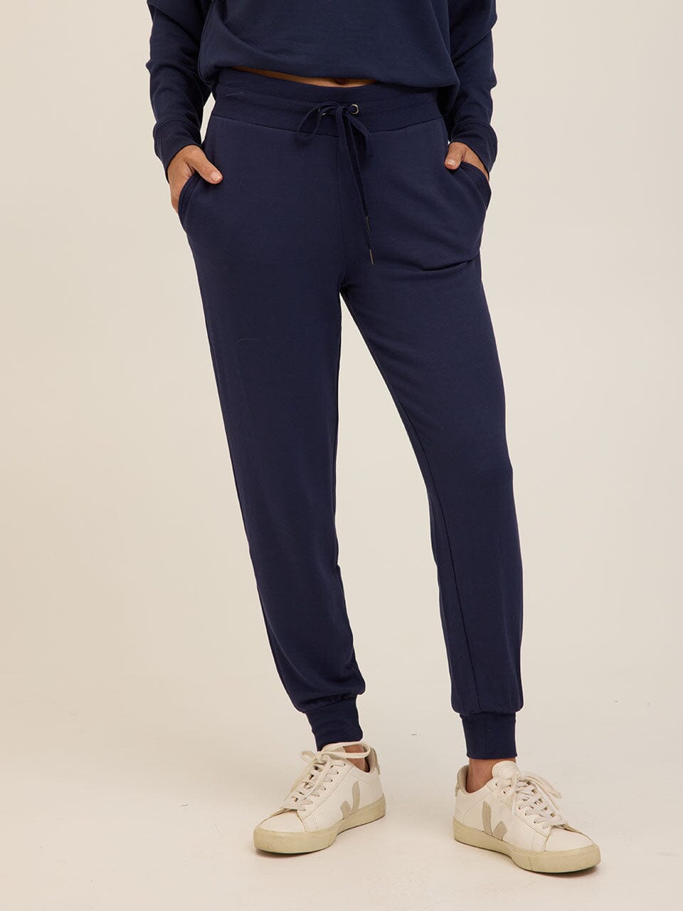 Women wearing comfortable navy blue Core Feather Fleece joggers with a relaxed fit, mid-rise waist, and ribbed cuffs.