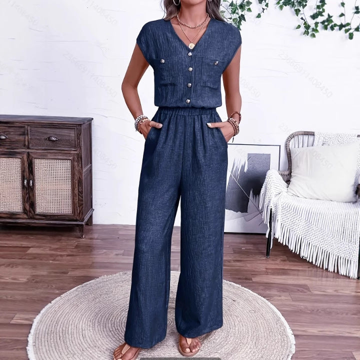 Woman wearing a navy blue minimalist V-neck jumpsuit with a button-front and elastic waist.