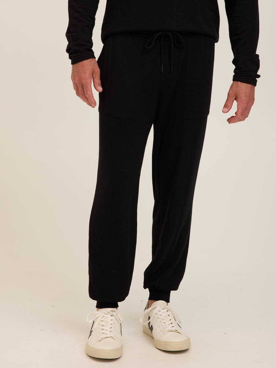 Men wearing black Core Feather Fleece Joggers in a minimalist sporty style.
