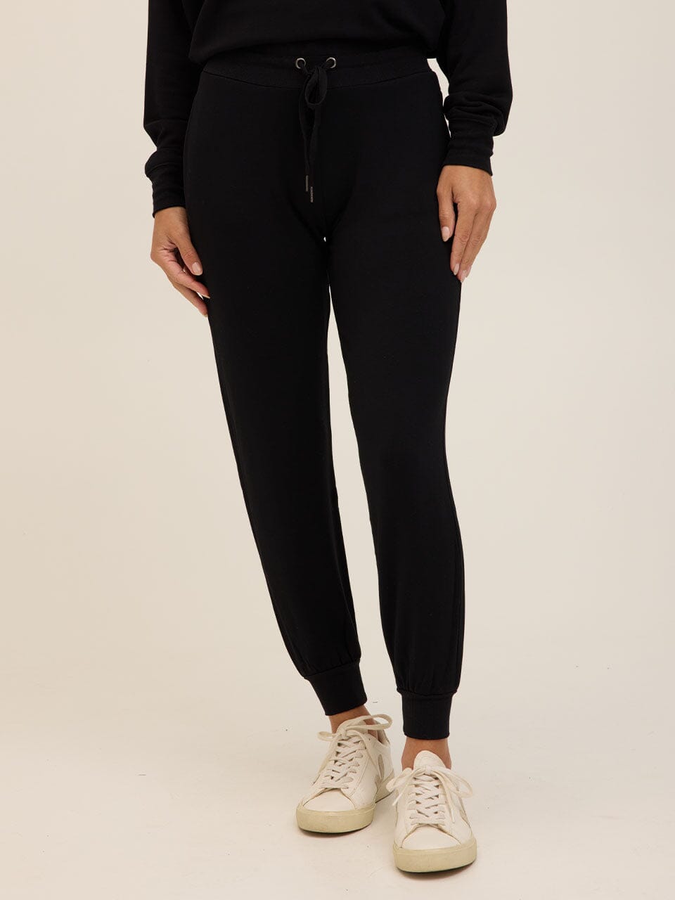 Women wearing black Core Feather Fleece joggers in a relaxed, tapered fit with ribbed ankle cuffs.