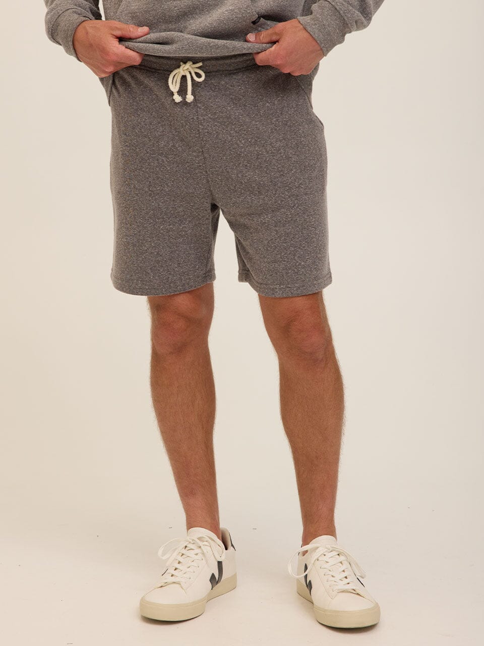 Men wearing comfortable grey triblend fleece shorts with side pockets and an adjustable drawstring waistband.