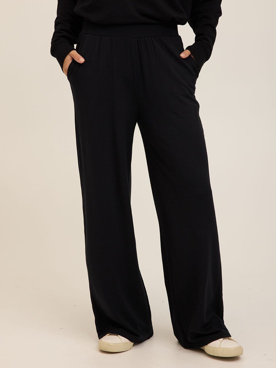 A woman wearing black relaxed wide-leg feather fleece sweatpants in a minimalist athleisure style.