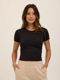 A woman wearing a fitted, cropped Core Luxe Jersey Crew Neck Tee in a solid color, showcasing the crew neckline and smooth fabric texture.