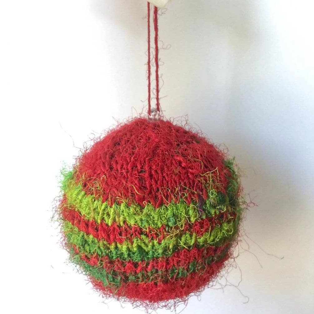 Close up of red and green striped knit Christmas ornaments hanging on a tree.
