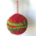 Close up of red and green striped knit Christmas ornaments hanging on a tree.