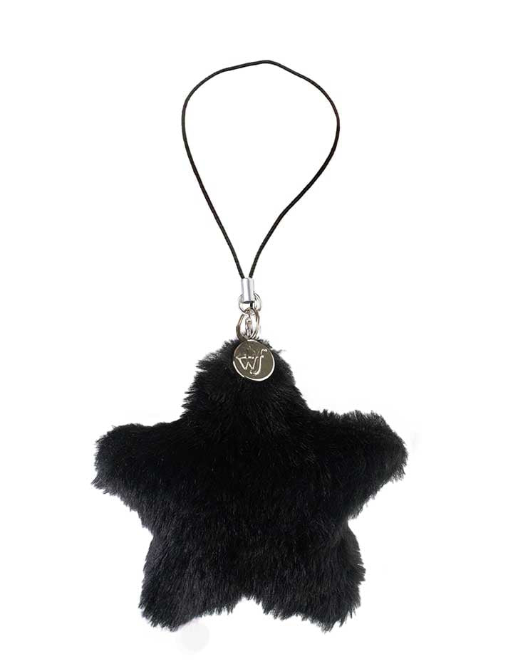 A black fluffy star-shaped phone charm with a small branded metal tag hanging from a thin black loop.
