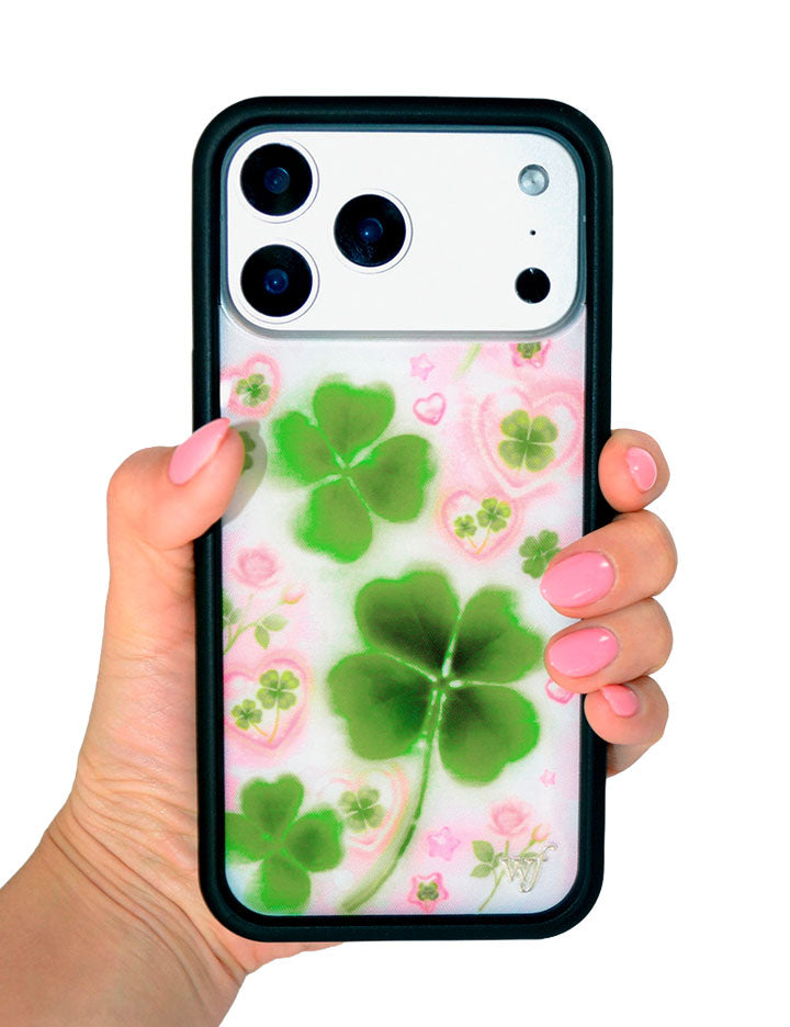 Phone case with green four-leaf clovers and pink flowers held by a hand