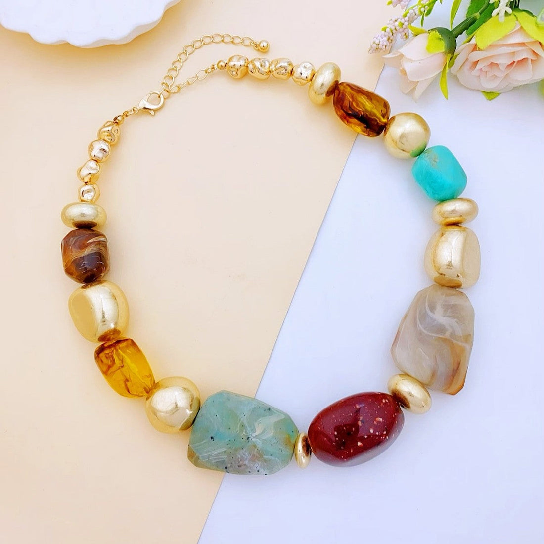 Close up of irregular marbled acrylic and resin statement necklace with gold beads