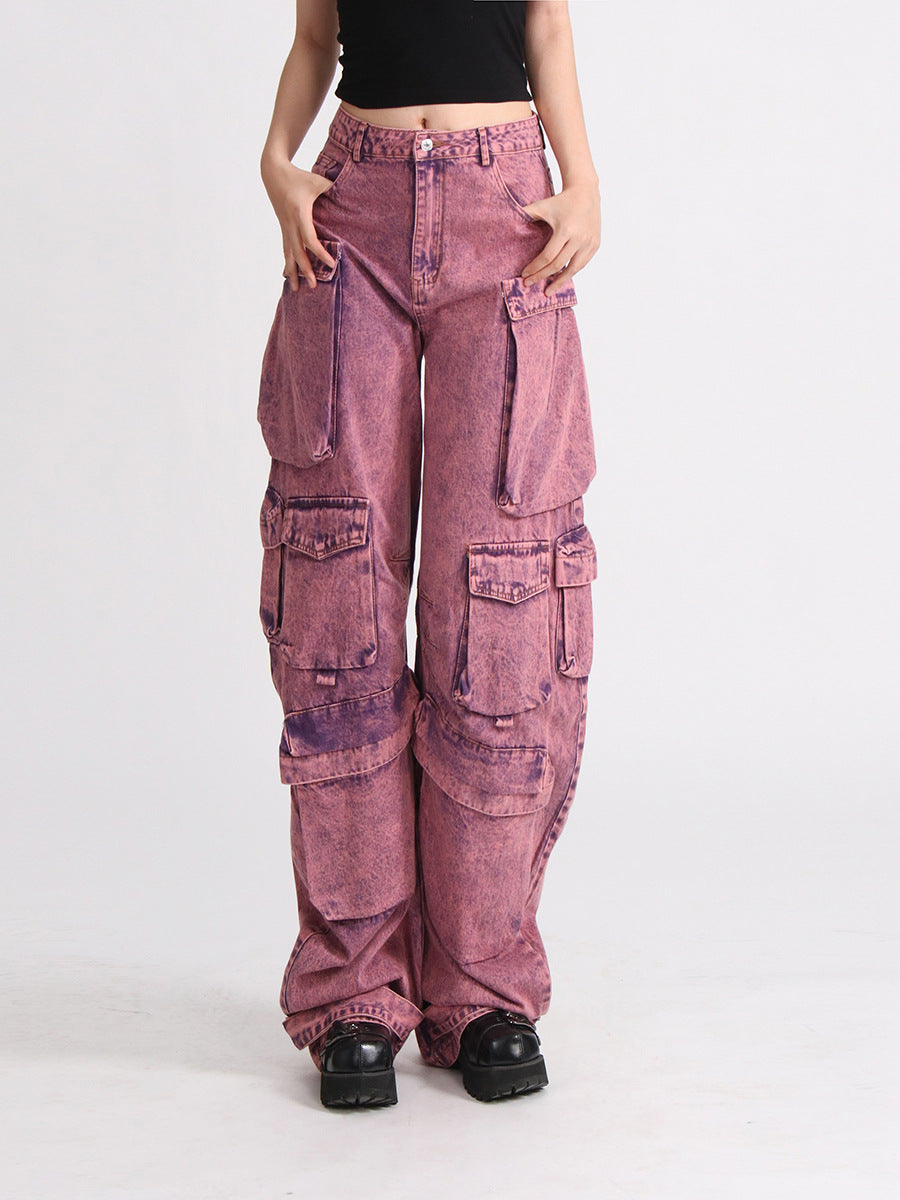 Model wearing pink acid wash high waist wide leg patchwork cargo jeans with multiple pockets, paired with a black crop top.