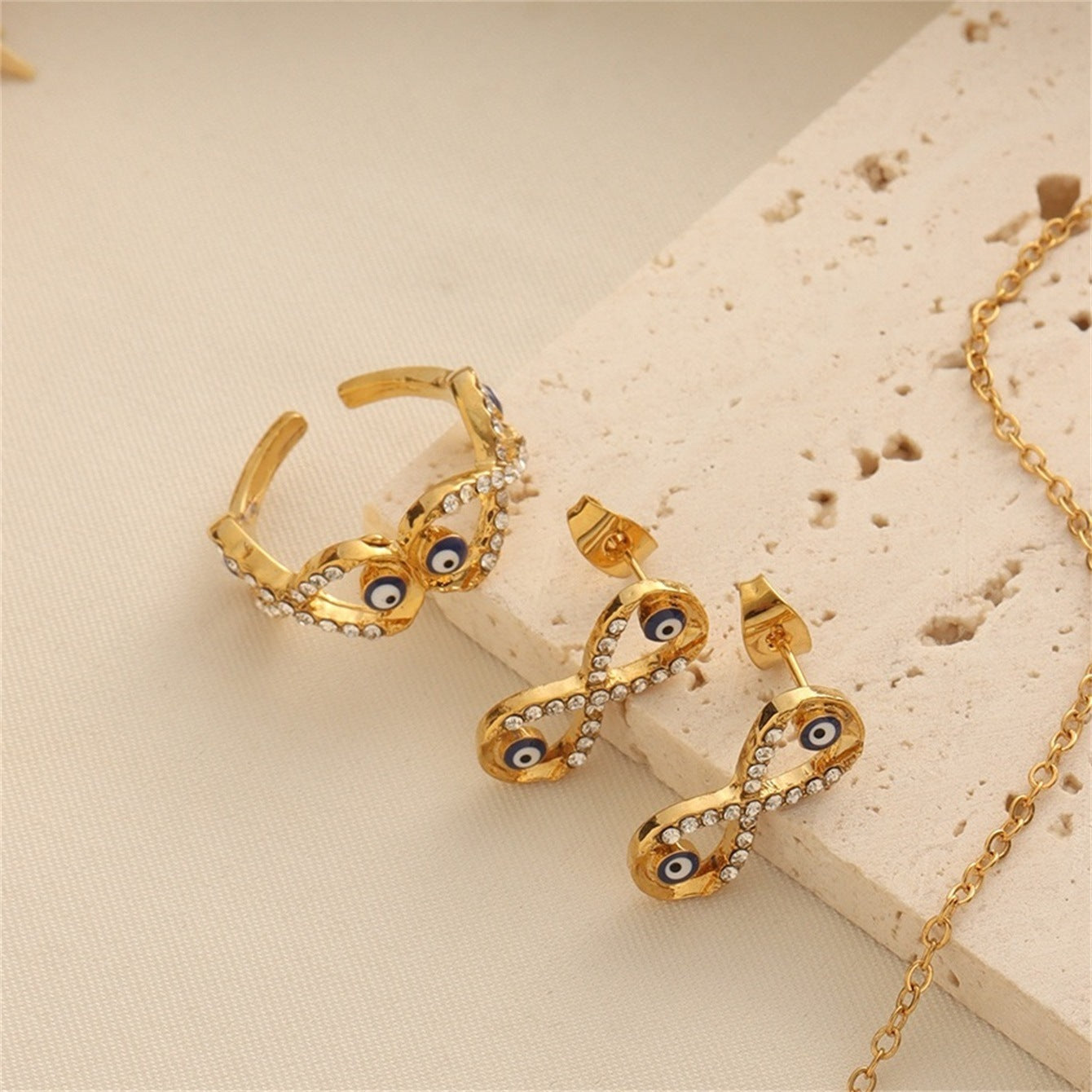 Gold-tone evil eye necklace, earrings, and ring set with sparkling white crystal accents.