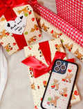 A two-pack of gift wrapping paper featuring an 'Oh Deer' fawn pattern with polka dots and a red gingham pattern with hearts.