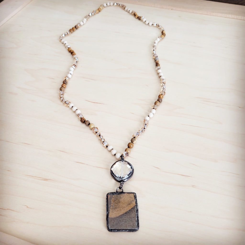 Long necklace featuring beige and brown Picture Jasper beads, clear crystal spacers, a faceted clear crystal accent, and a rectangular Jasper pendant in a dark metal setting.