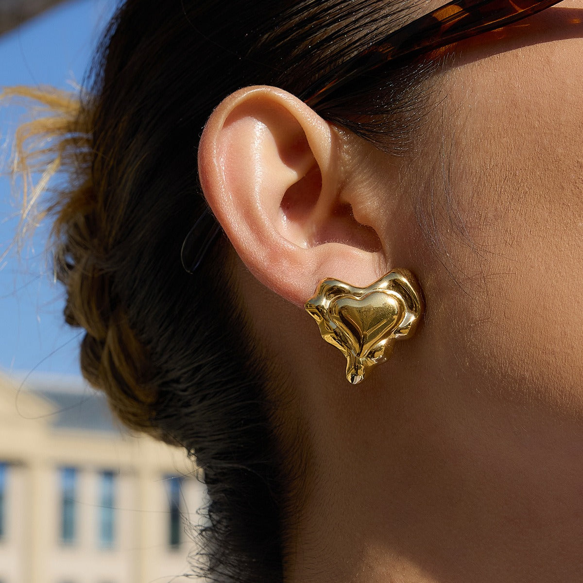 A pair of elegant gold heart-shaped stud earrings featuring a minimalist design perfect for autumn fashion.