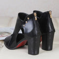A pair of black and tan women's mid-heel cutout sandals featuring a peep-toe and back zipper closure on a white surface.