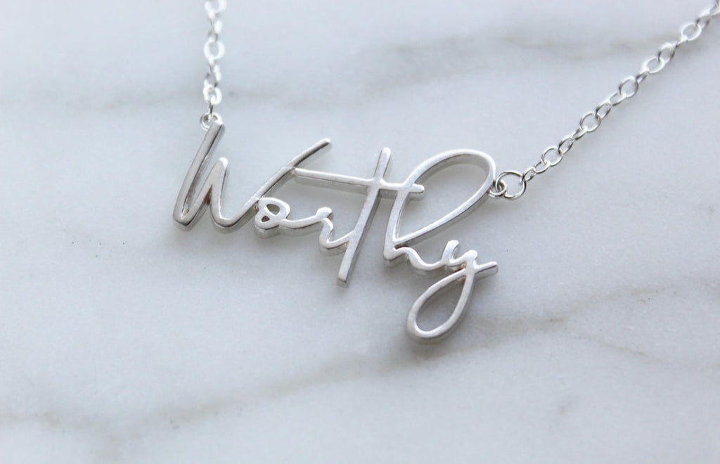 Worthy script word necklace in silver-tone finish on display