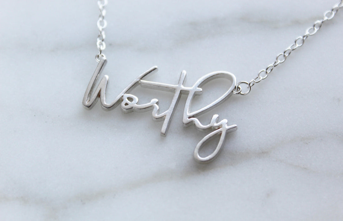 Worthy script word necklace in silver-tone finish on display