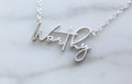 Worthy script word necklace in silver-tone finish on display
