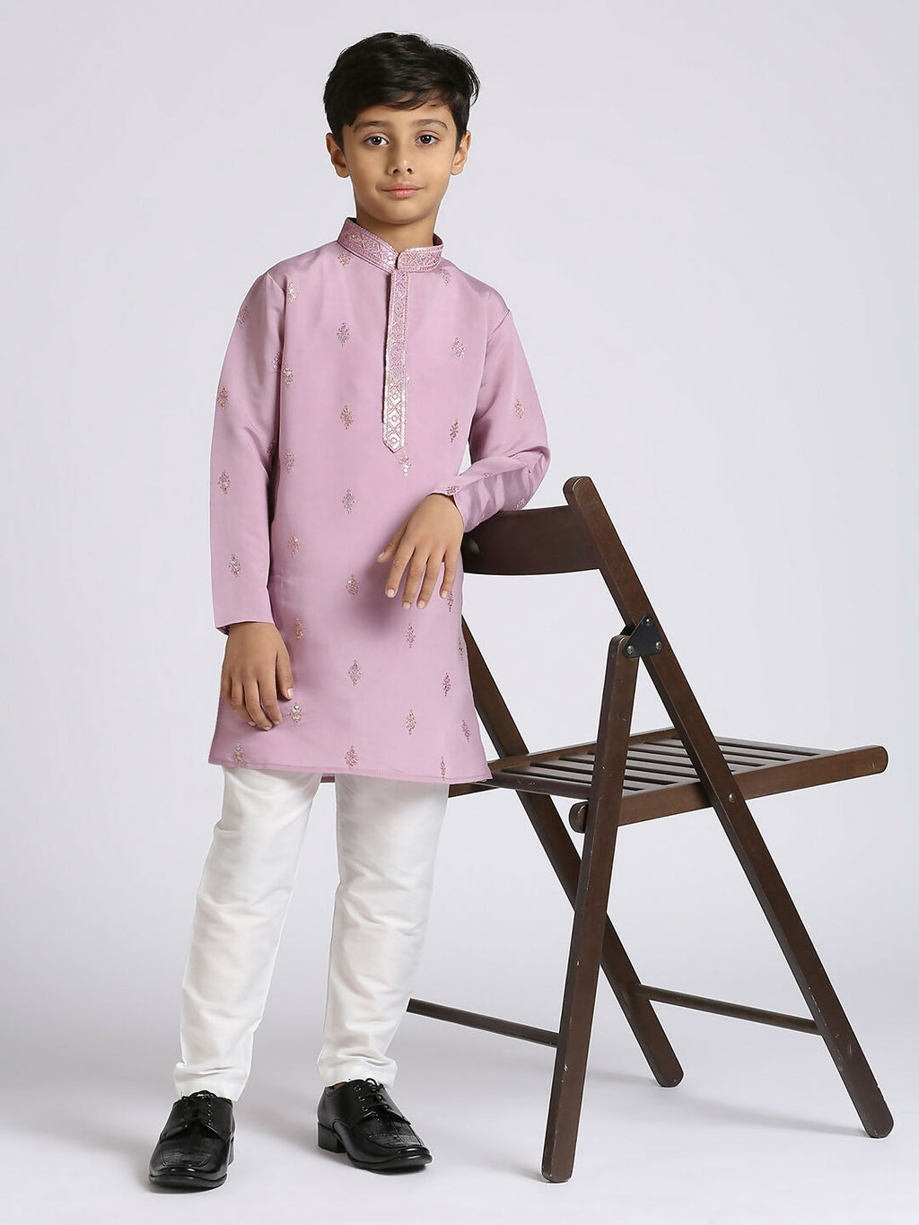Front view of a young boy wearing a vibrant purple long-sleeved kurta with detailed silk sequence embroidery and matching pyjama bottoms.
