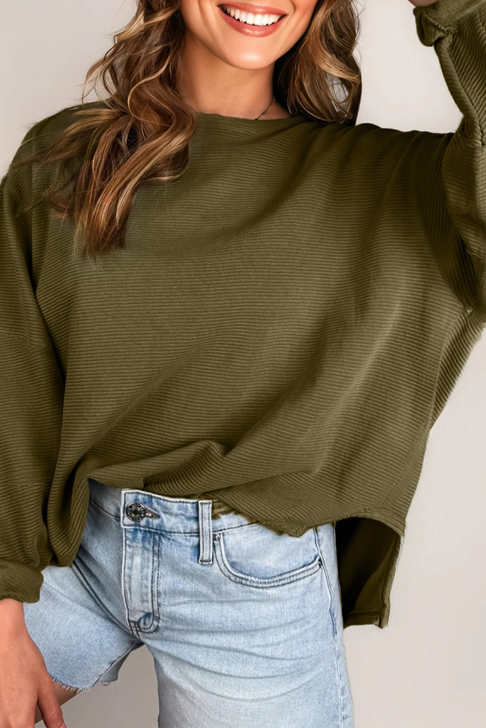 Close-up of a solid olive green ribbed knit long sleeve top with patchwork detail.