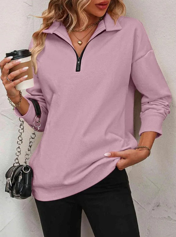 Woman wearing a light purple long-sleeve top with a zipper, holding a coffee cup.