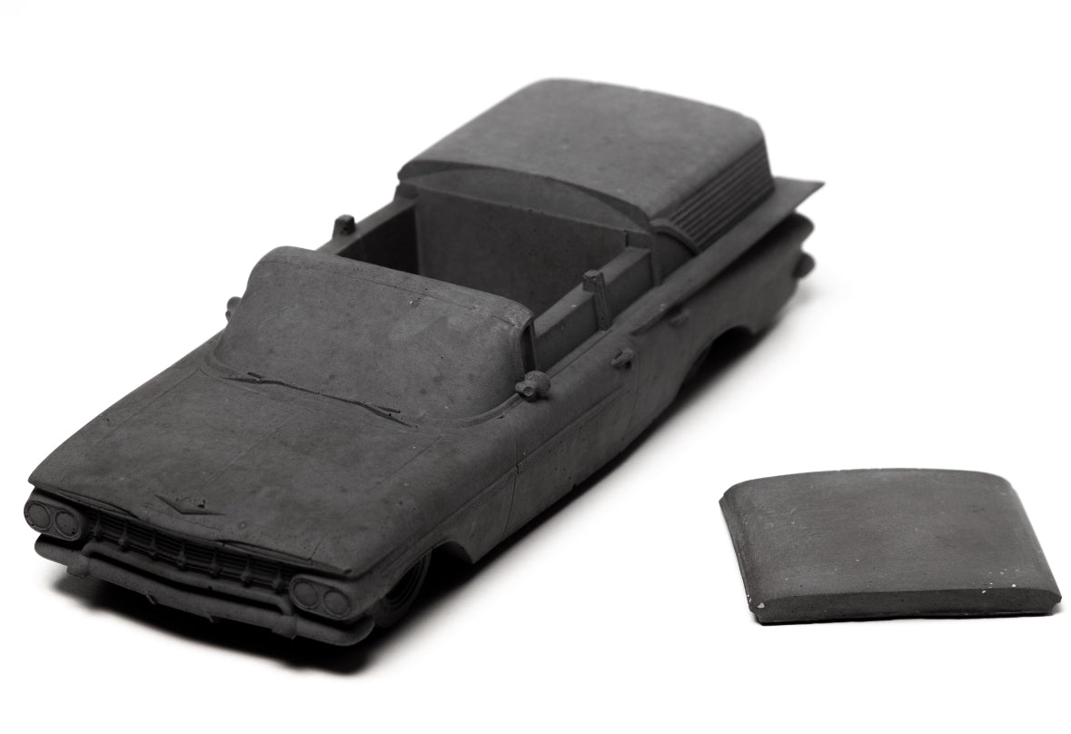 A monochromatic concrete incense burner inspired by a 1959 Chevrolet Brookwood, styled in a modern industrial living room.