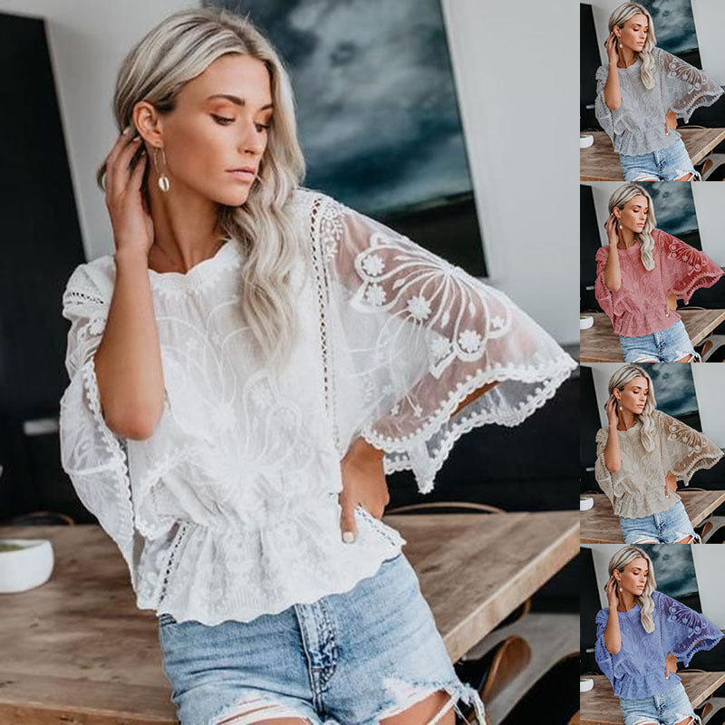 A woman wearing a white lace trim batwing sleeve blouse with a flattering cinched waist paired with denim shorts.