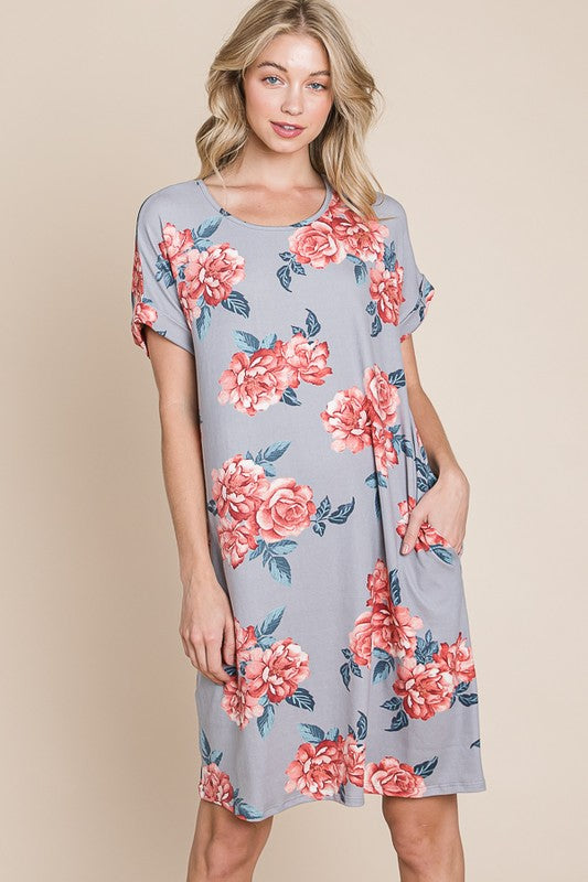 Woman wearing a floral print short sleeve t-shirt dress with side pockets.
