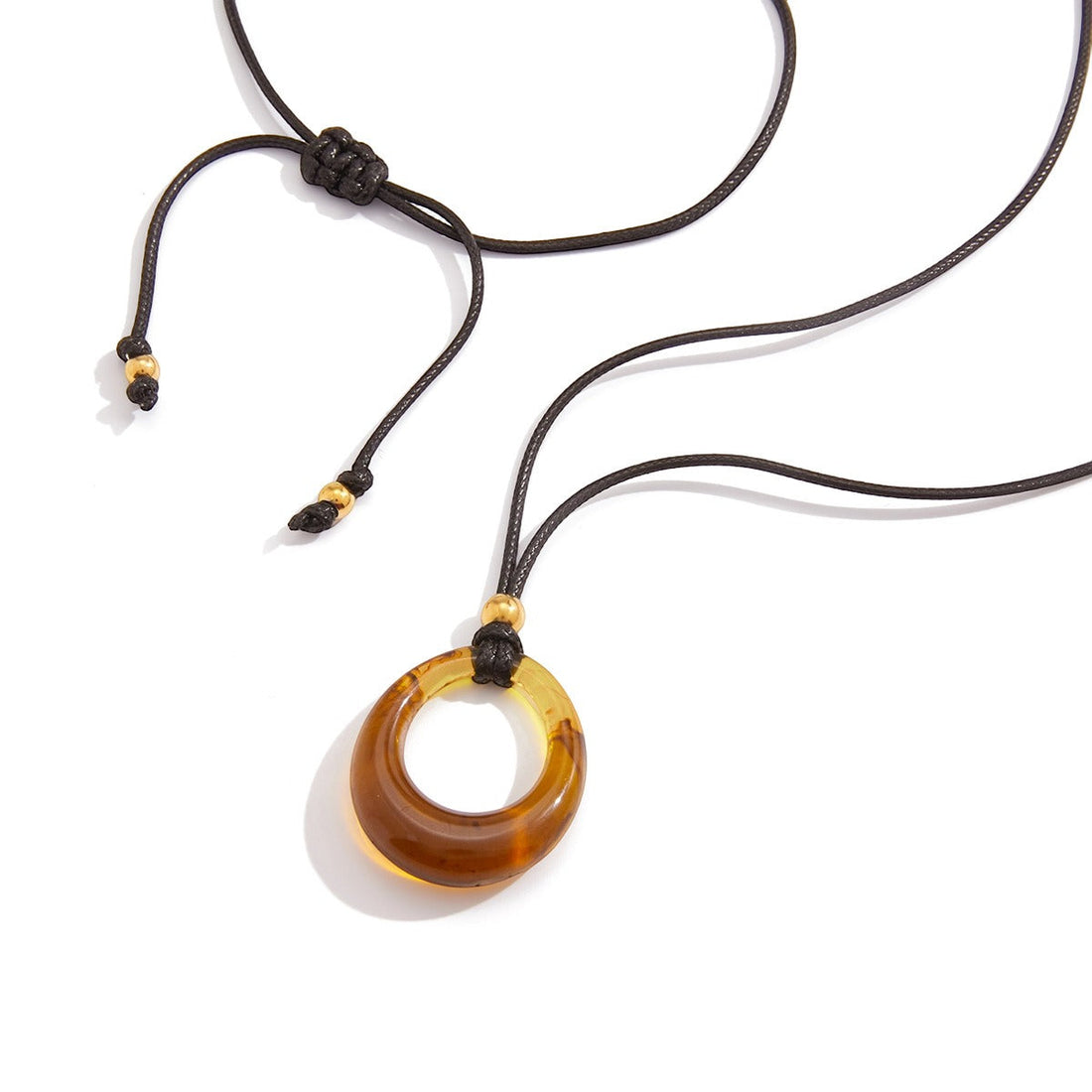 Long necklace featuring an amber-colored resin pendant on a minimalist black cord.