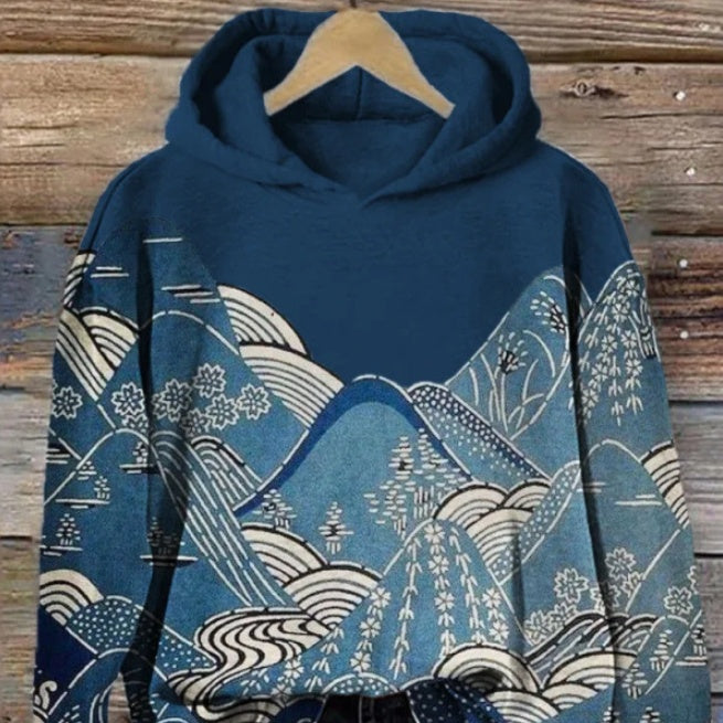 Women wearing long sleeve hooded pullovers with blue mountain landscape print and green fish graphic print