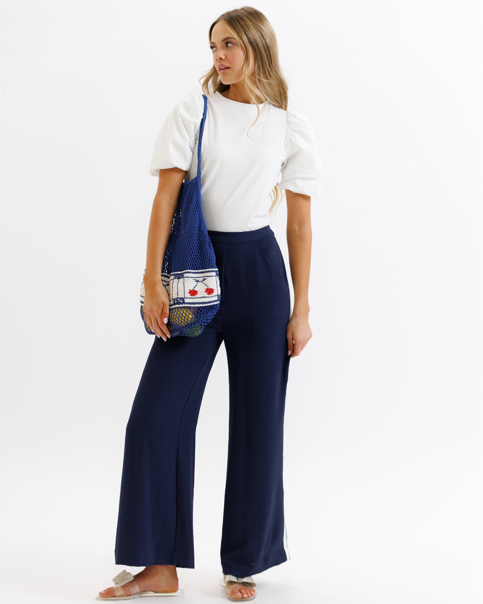 Model wearing dark blue wide leg Parisian pants with a back elastic waistband and side stripe detail