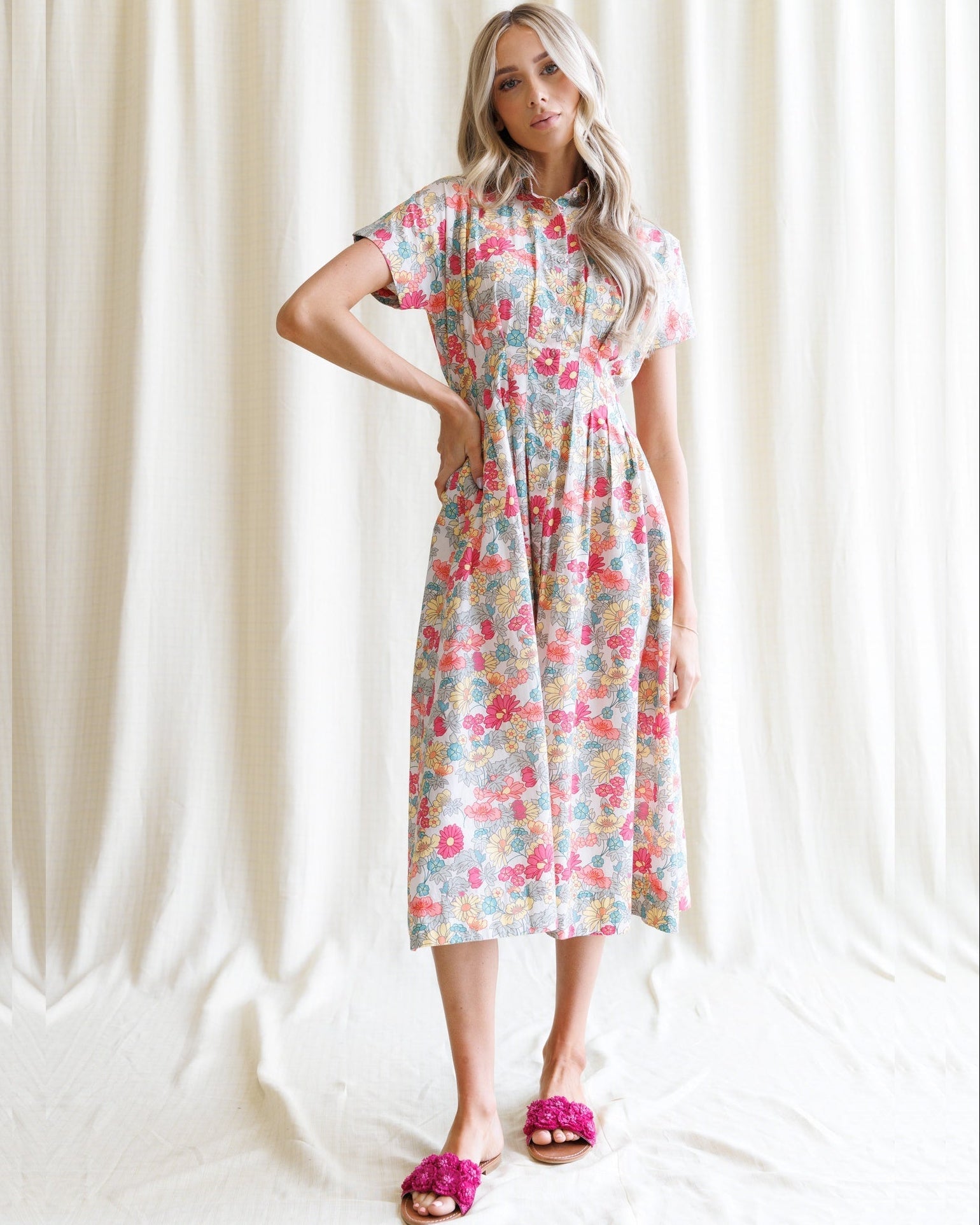Woman wearing a midi-length floral print shirtdress with a collared neckline and kimono sleeves.