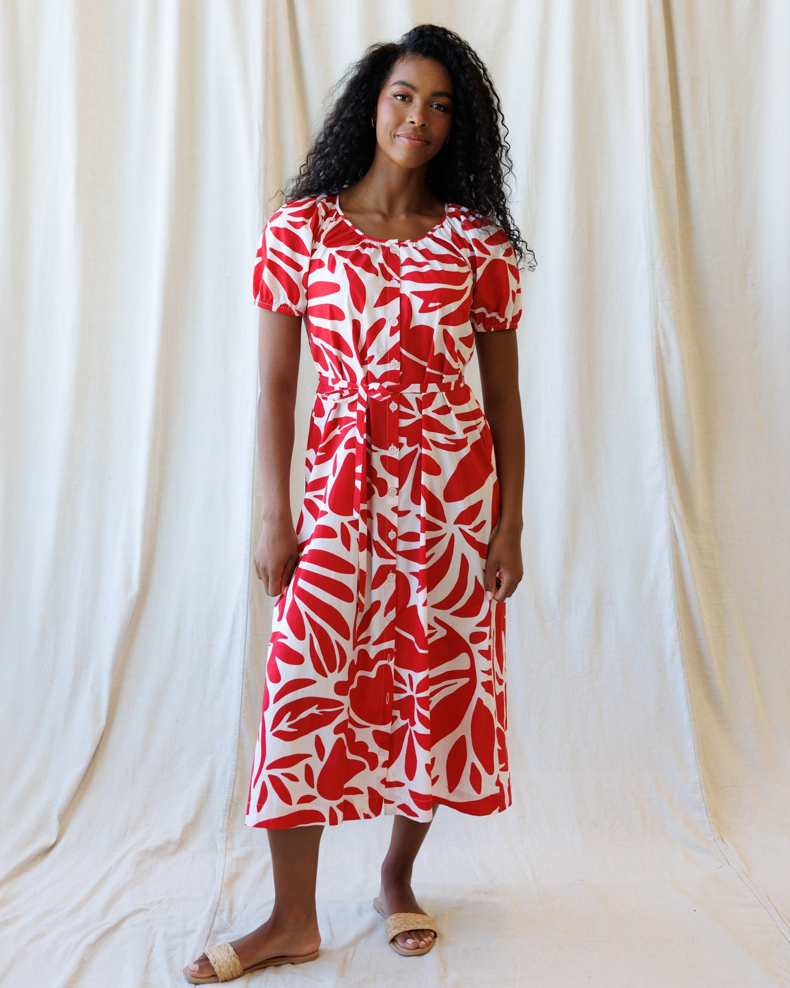 A bohemian-inspired red and white botanical print cotton maxi dress with a tie belt and peasant sleeves.