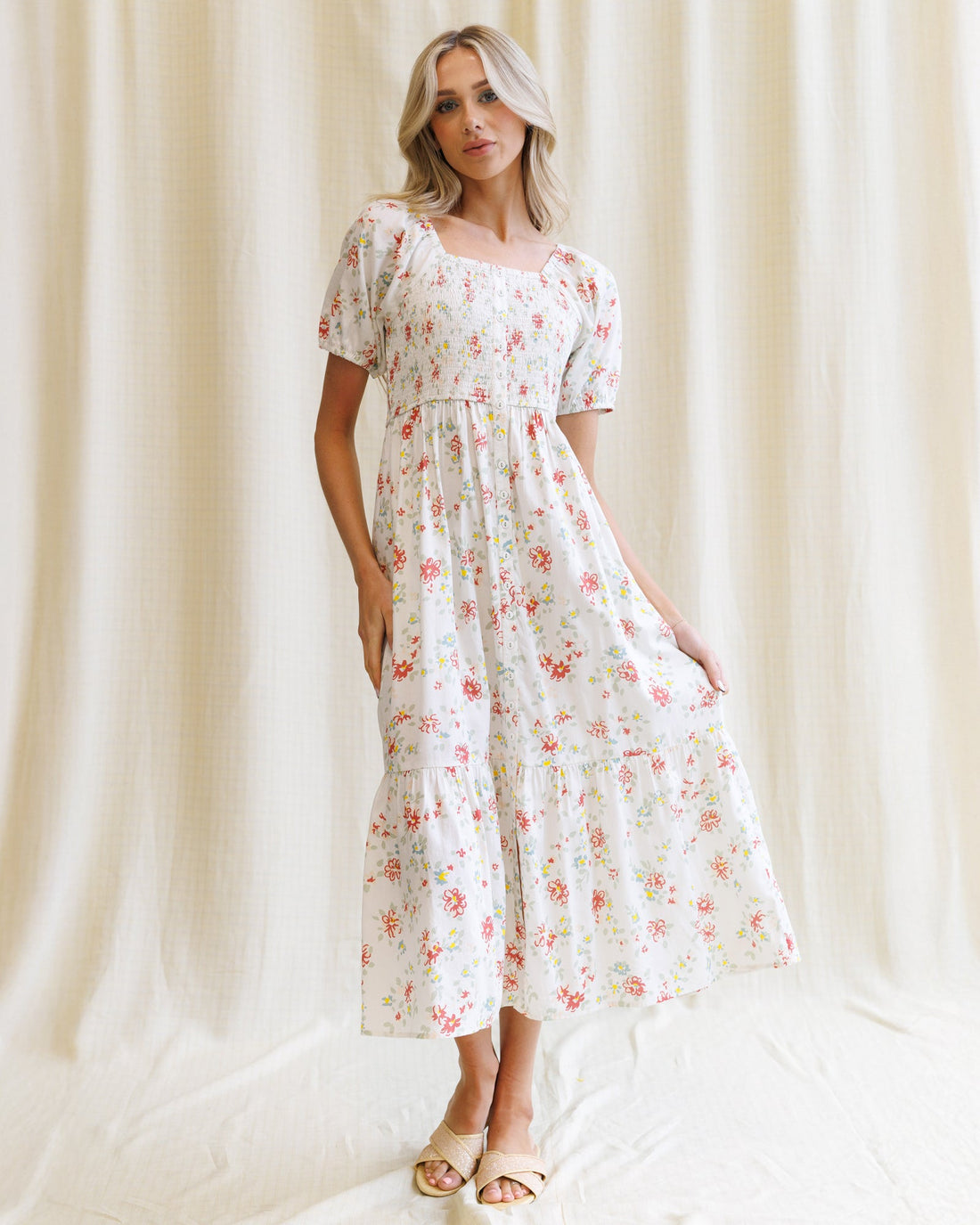 A fit-and-flare floral cotton maxi dress featuring a smocked bodice, square neckline, and puff sleeves.