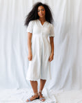 Woman wearing a Swiss dot midi dress with puff sleeves and pintuck detailing in white