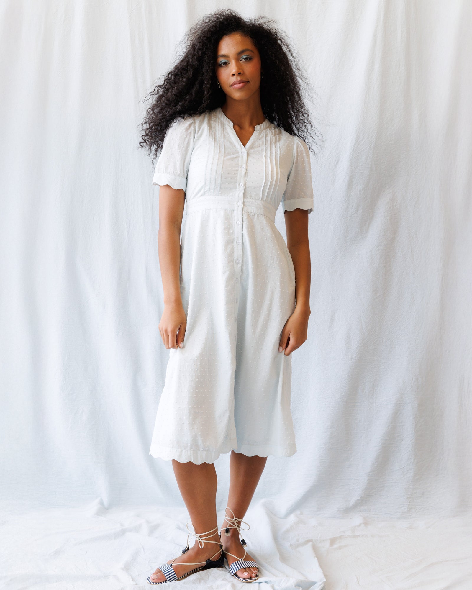 Woman wearing a Swiss dot midi dress with puff sleeves and pintuck detailing in white