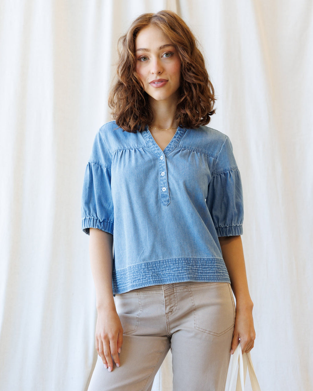 Model wearing a blue Portside Chambray Popover with puff sleeves and button placket