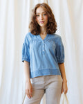 Model wearing a blue Portside Chambray Popover with puff sleeves and button placket