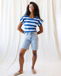 A pair of high-rise, light-blue denim shorts with a raw hem and relaxed fit, shown against a neutral background.