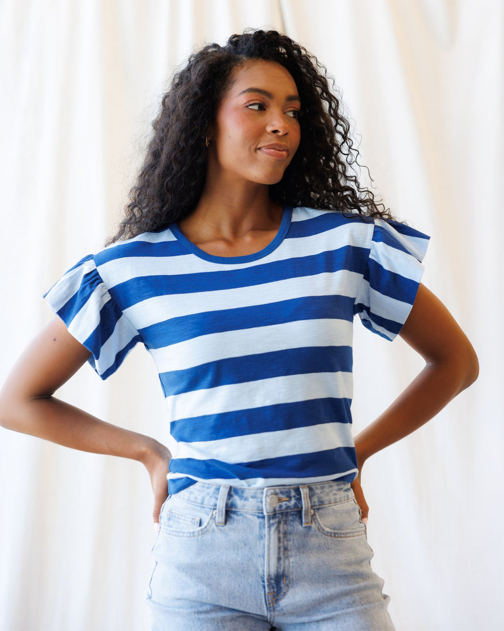 Model wearing a blue, light blue, and white striped cotton tee with short flutter sleeves