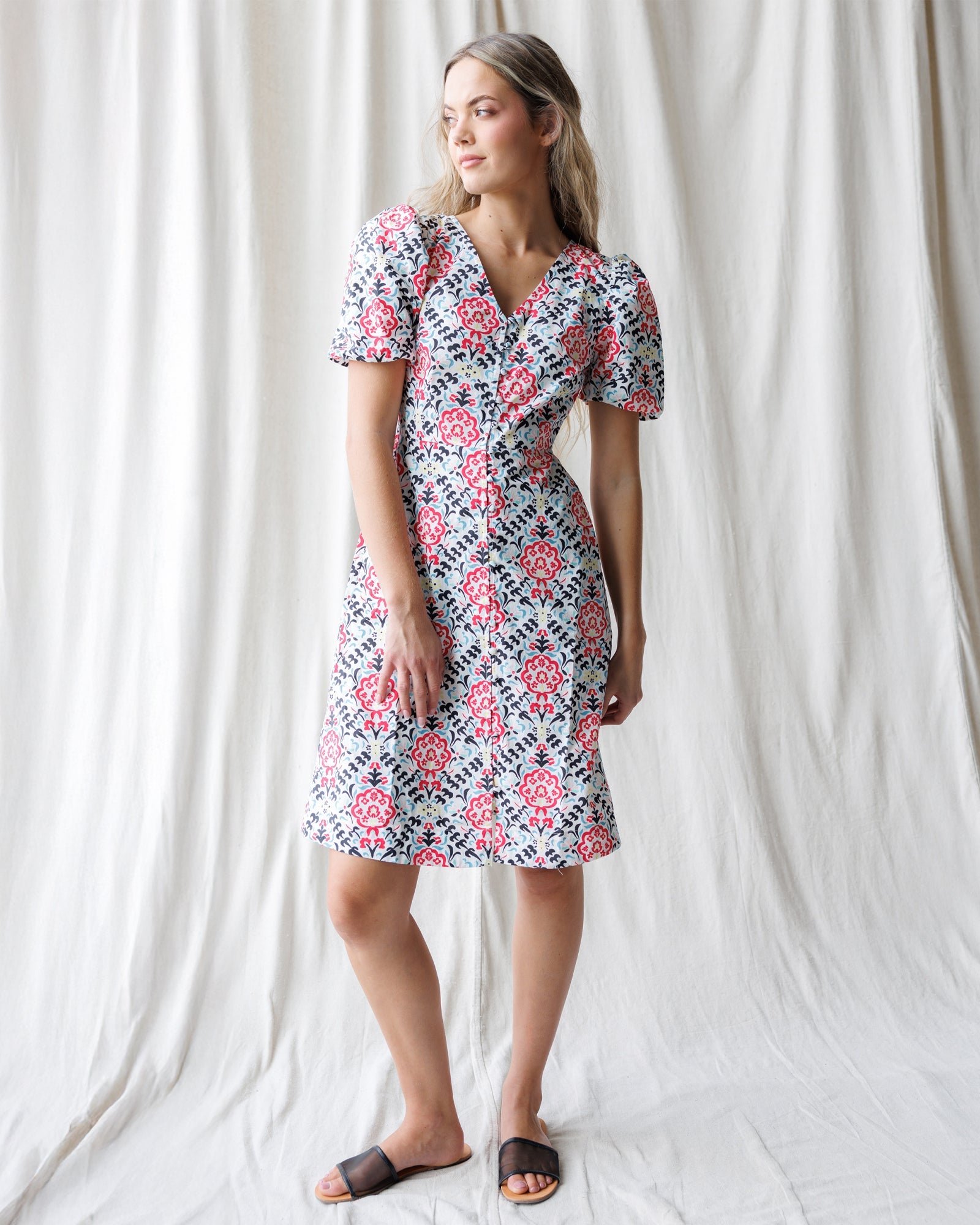 Woman wearing a cotton A-line Capri dress with puff sleeves and a button-down front