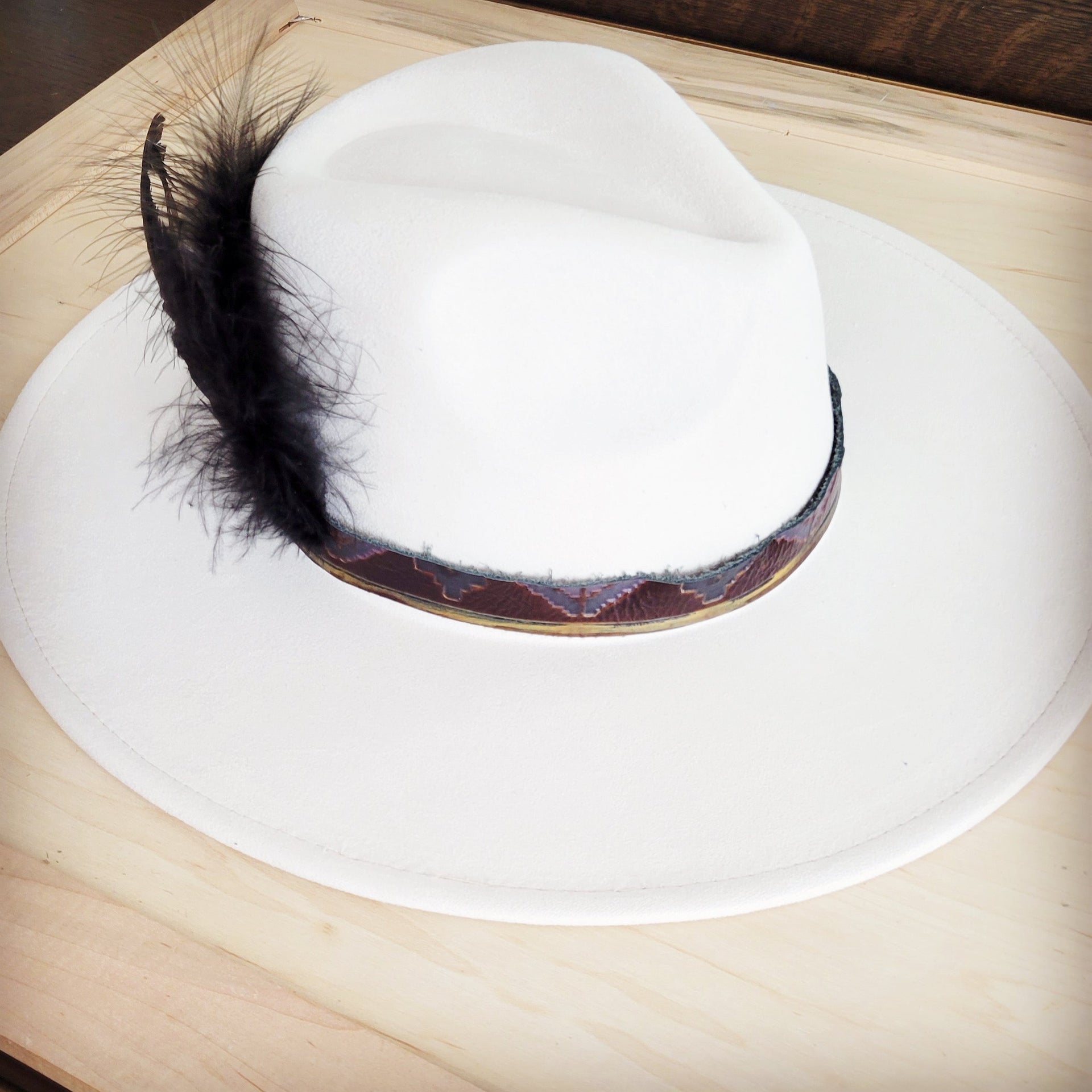 Magenta Navajo pattern leather hat band with black feather accents shown flat and wrapped around a white wide-brim hat.