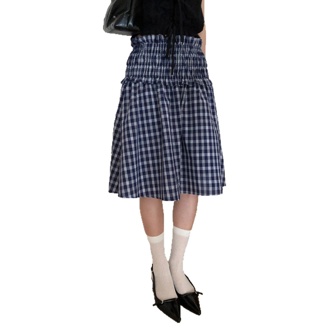 Model wearing a blue and white plaid smocked waist midi skirt with a black top and black shoes.
