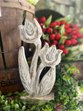 A decorative whitewashed wooden tulip figurine displayed on a rustic background.