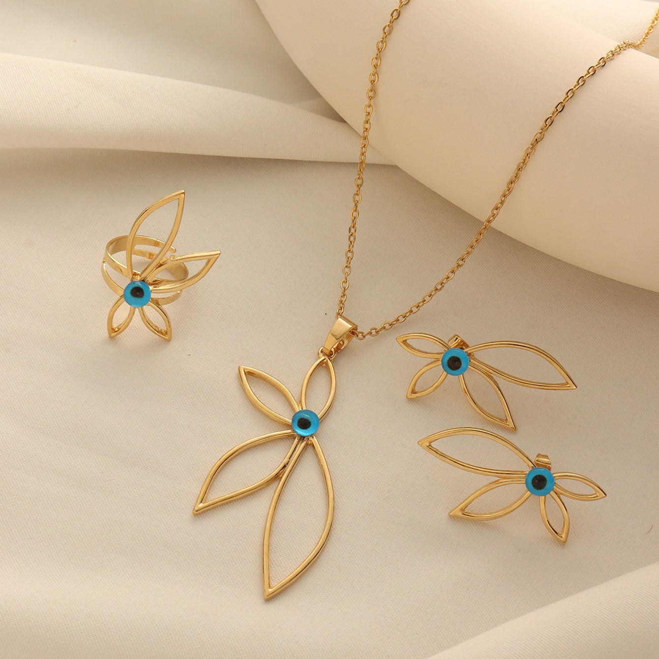 Gold-tone petal shaped jewelry set featuring blue evil eye centers, including a necklace, earrings, and a ring.