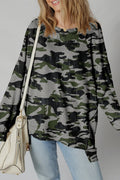 A woman wearing a camo print drop shoulder sweatshirt with an uneven hem, styled with light wash jeans.