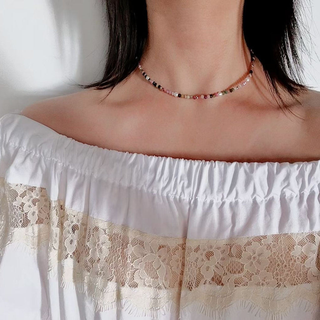 A handwoven natural tourmaline and freshwater pearl beaded necklace with geometric oval elements.